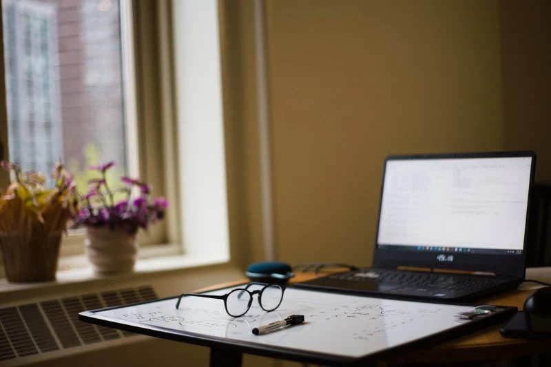 Zdjęcie przedstawia laptopa, okulary i biurko nauczyciela w szkole